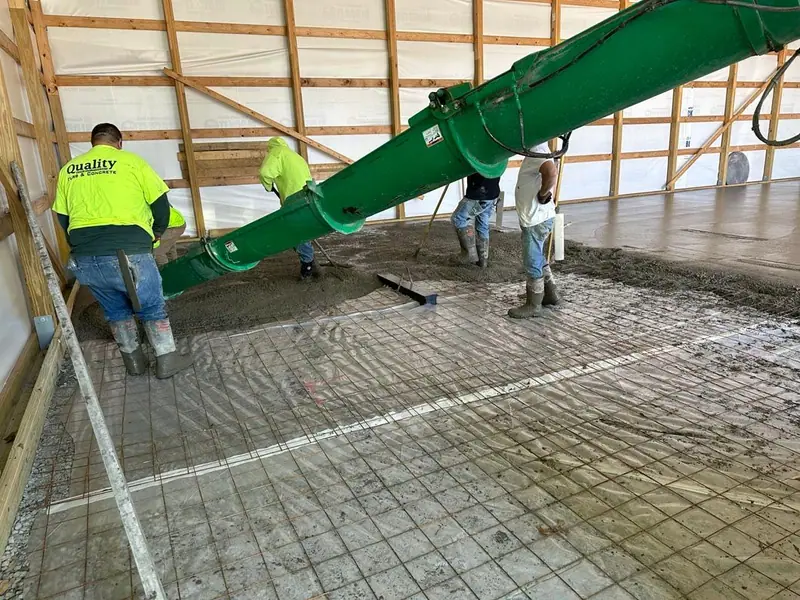 Crew placing concrete over rebar mesh inside a large building