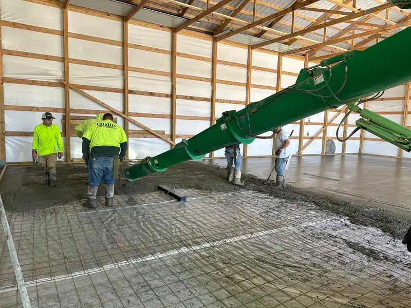 Pump boom placing concrete over rebar mesh inside a large building