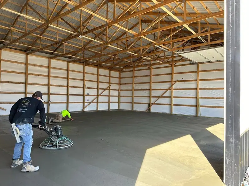 Crew power-troweling a new concrete floor inside a large building