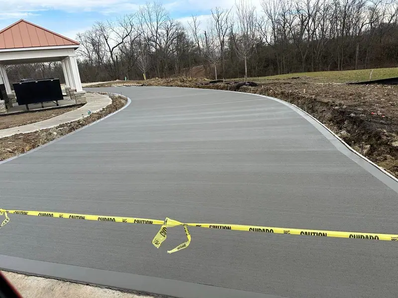 Finished curved concrete drive beside a neighborhood pavilion