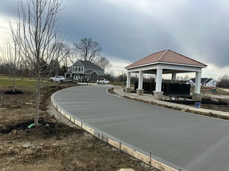 New concrete drive curving past a community pavilion