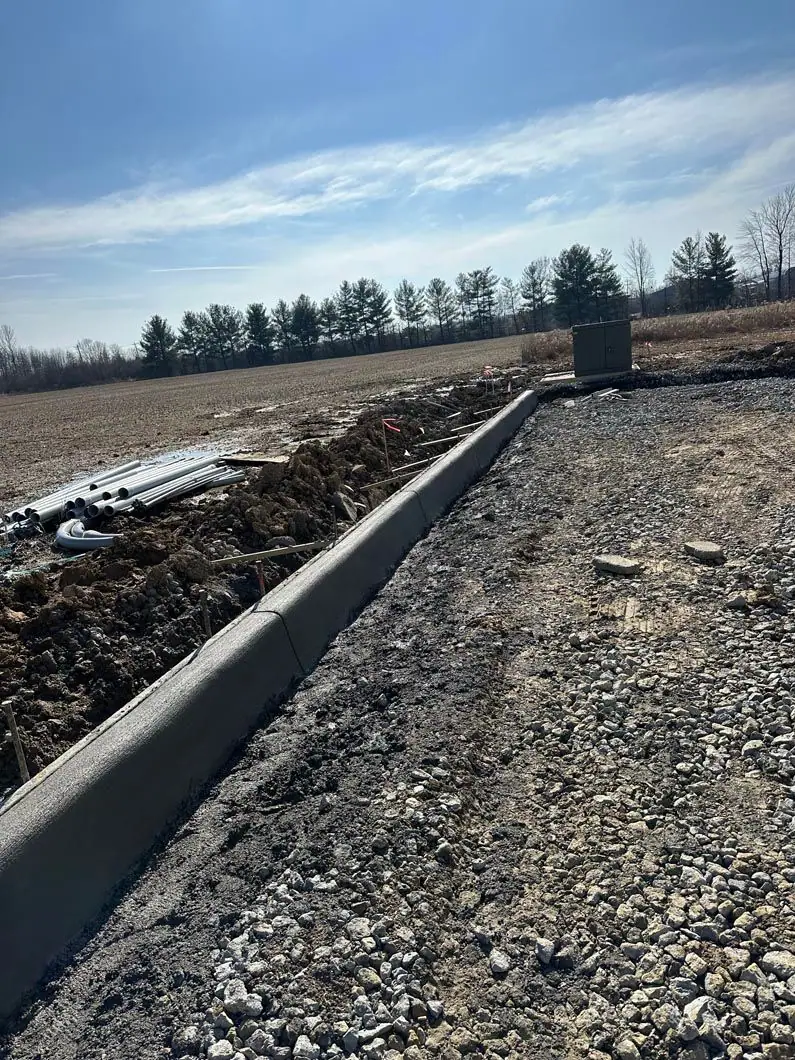 Freshly formed concrete curb beside a gravel base