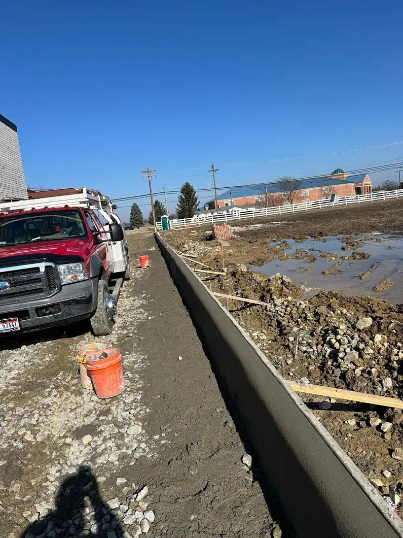 Freshly formed concrete curb beside a gravel base