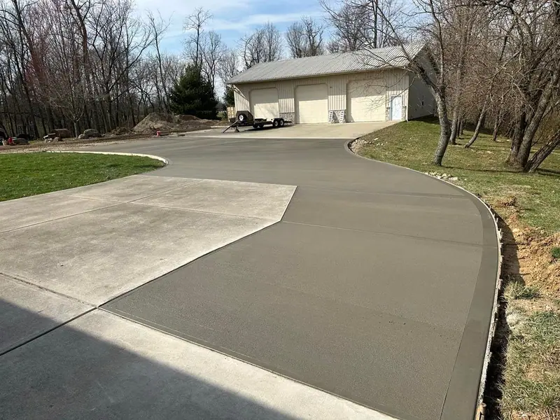 New curved concrete driveway leading to a detached garage