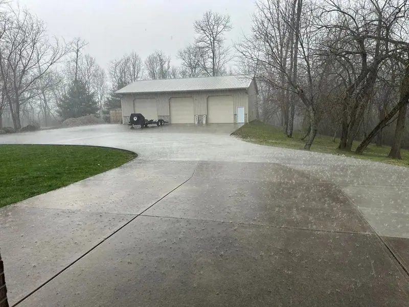 Long concrete driveway curving toward a detached garage