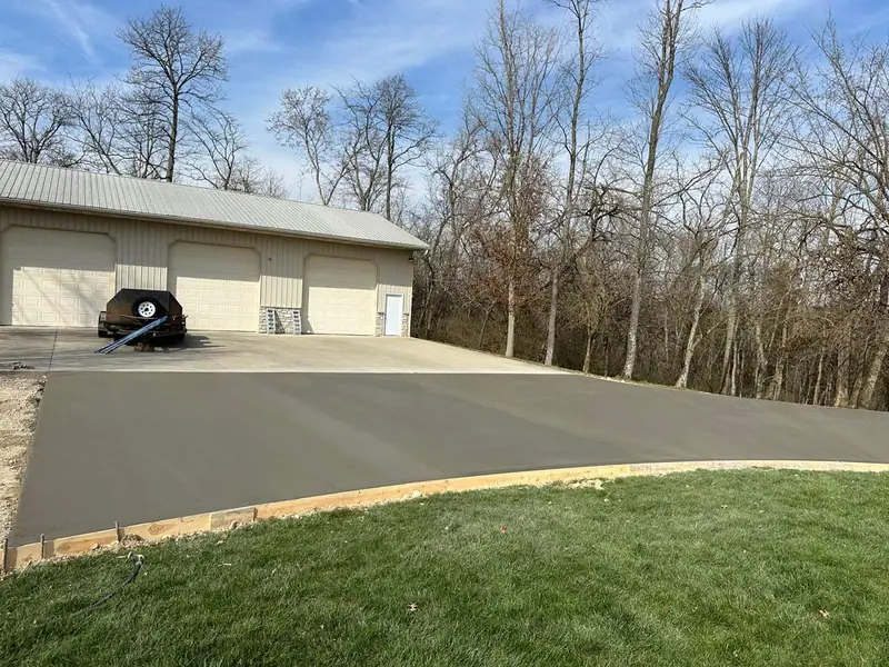 Newly poured concrete driveway leading to a three-car garage