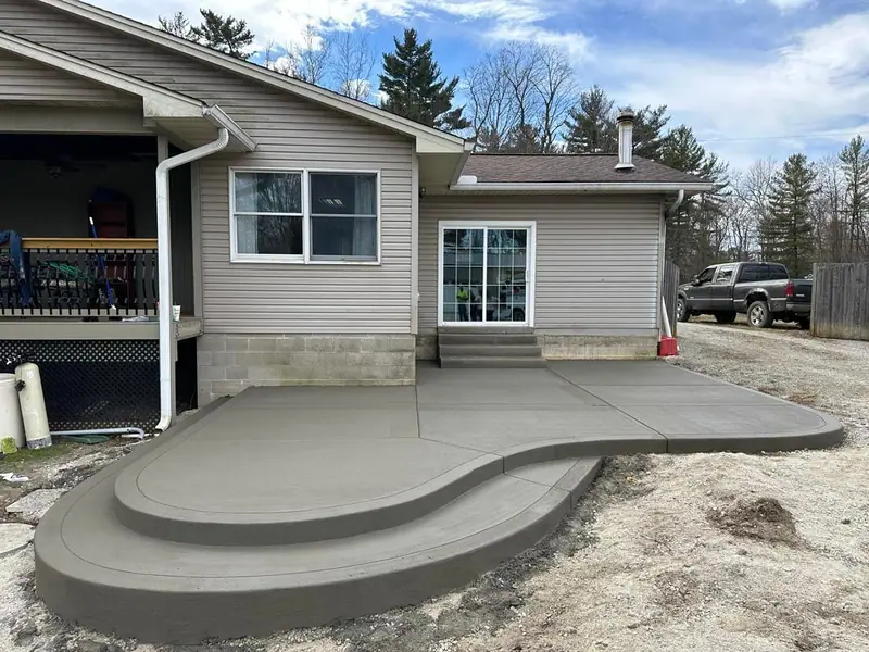 Rounded concrete patio step behind a house