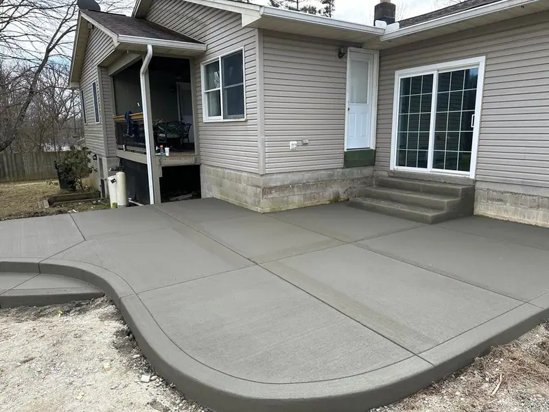 Poured concrete patio with rounded edge wrapping the back of a house