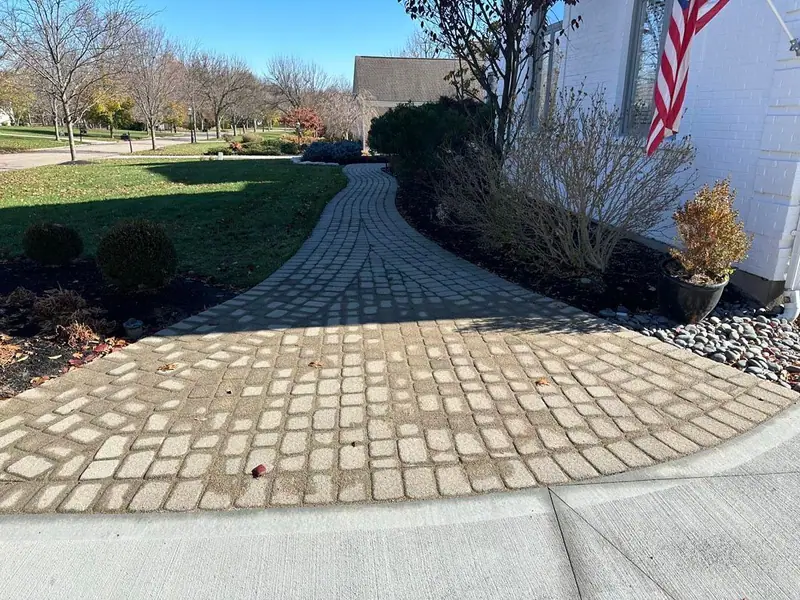 Brick-pattern decorative concrete walkway curving beside a lawn